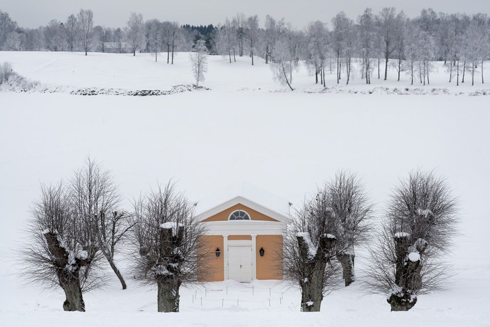 Et lite gult hus i et snødekt landskap.