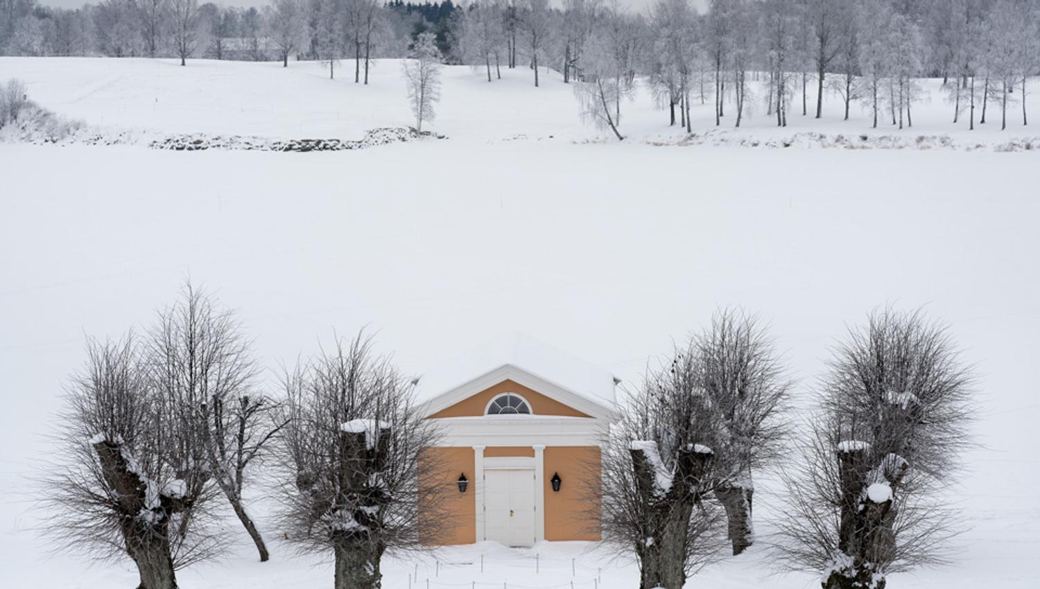 Et lite gult hus i et snødekt landskap.