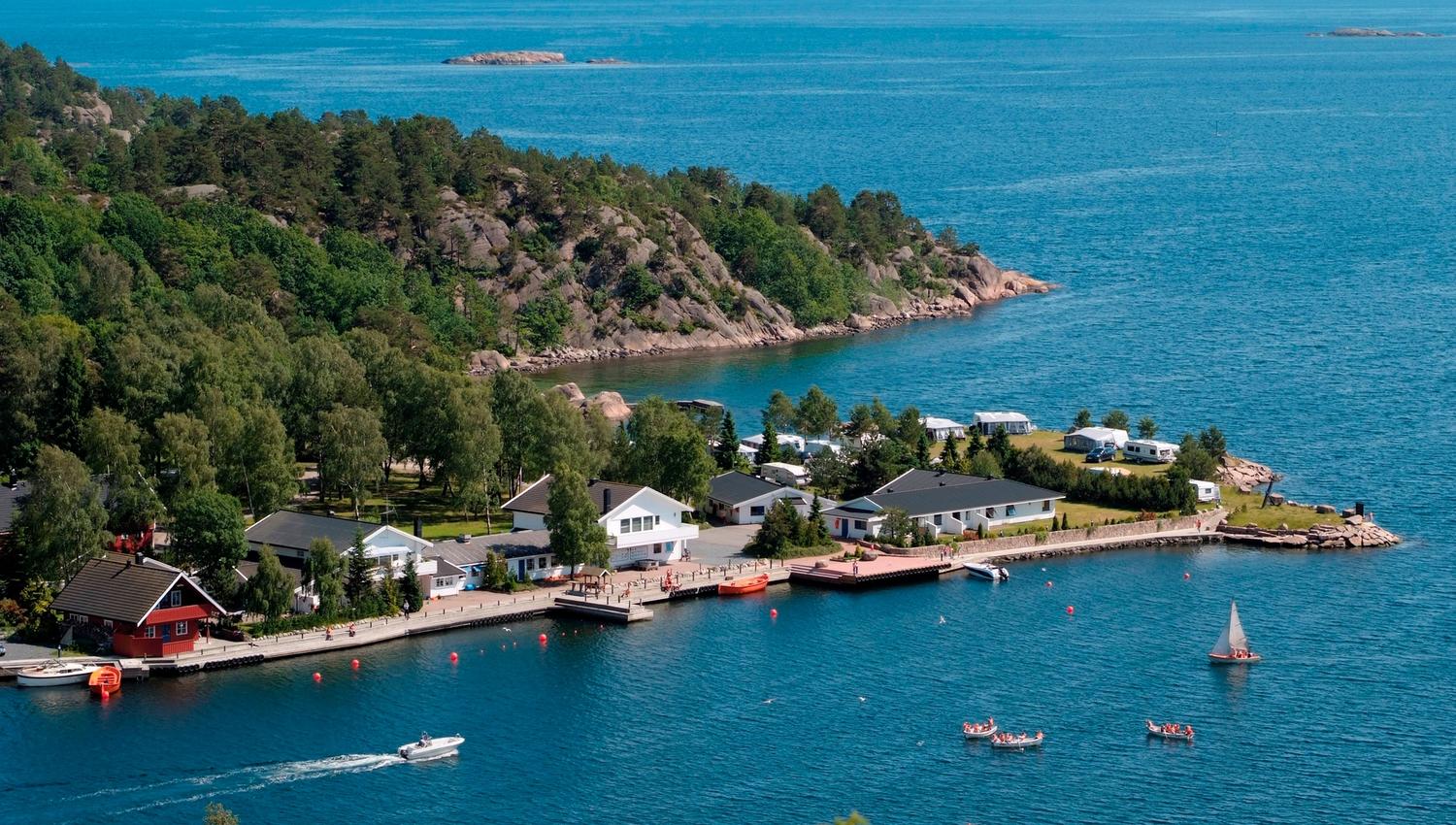 Oversiktsbilde over campingplass, hav og båter som kjører forbi