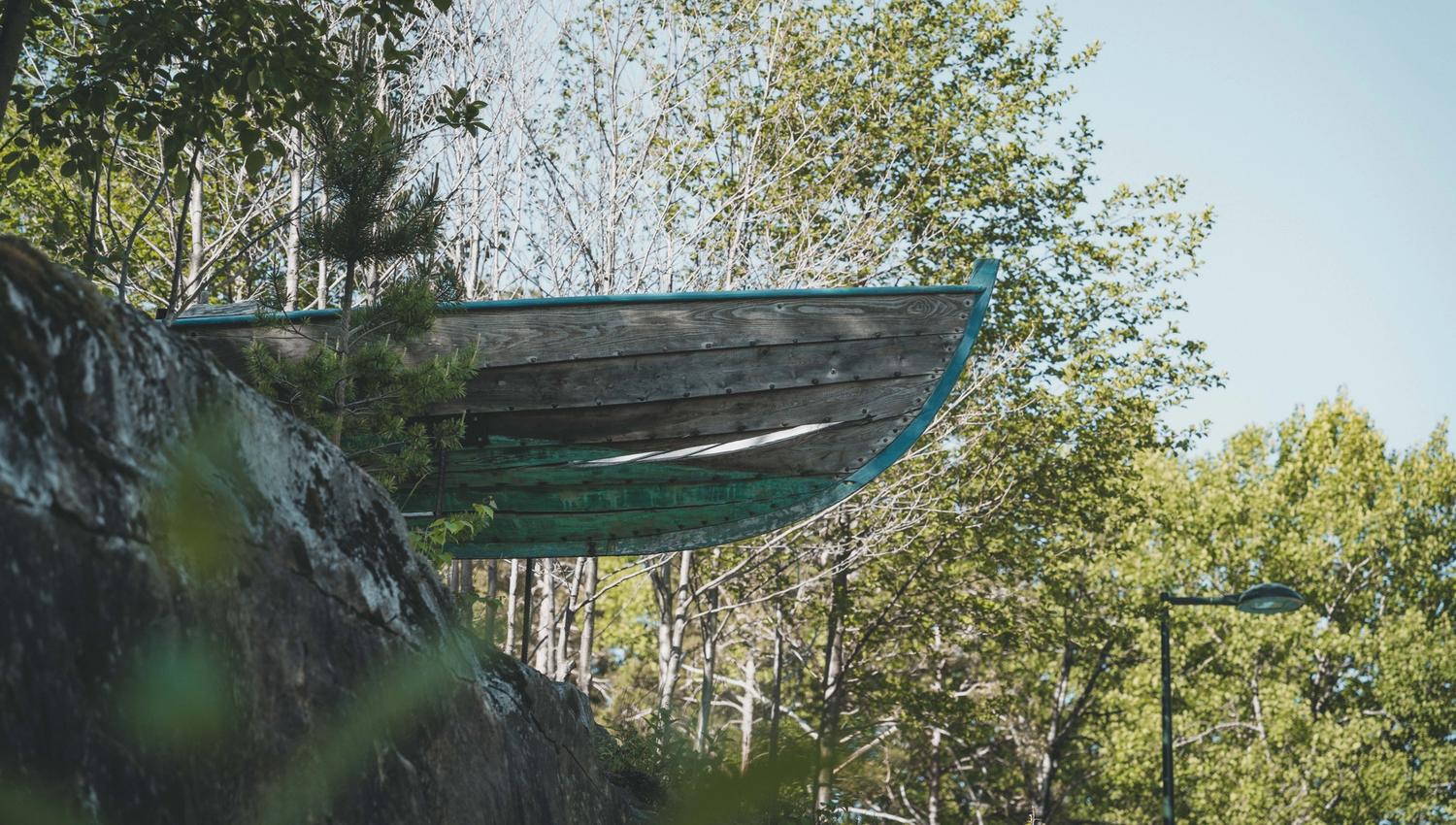 En kunstinstallasjon som viser fronten av en trebåt som stikker ut fra toppen av en ås.