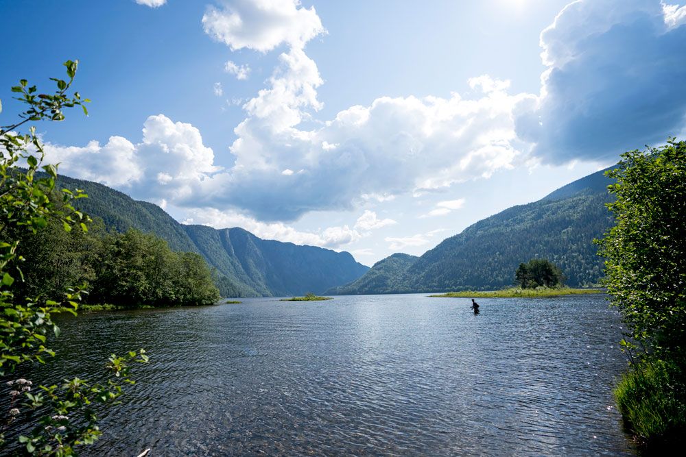 Mann står i vannet og fisker