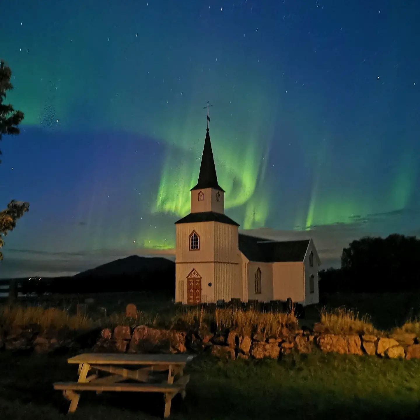 traditional church with aurora sky above it