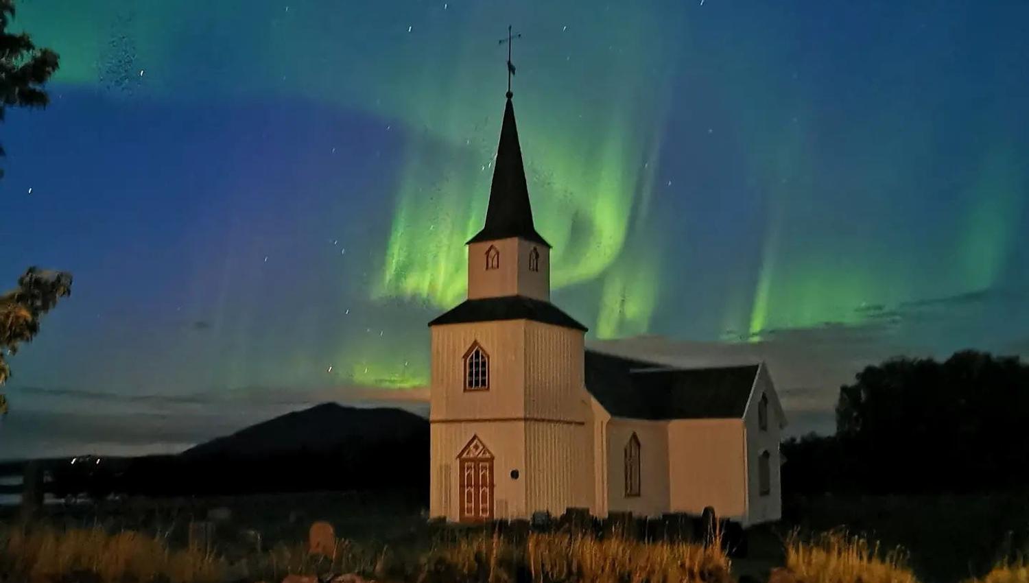 traditional church with aurora sky above it
