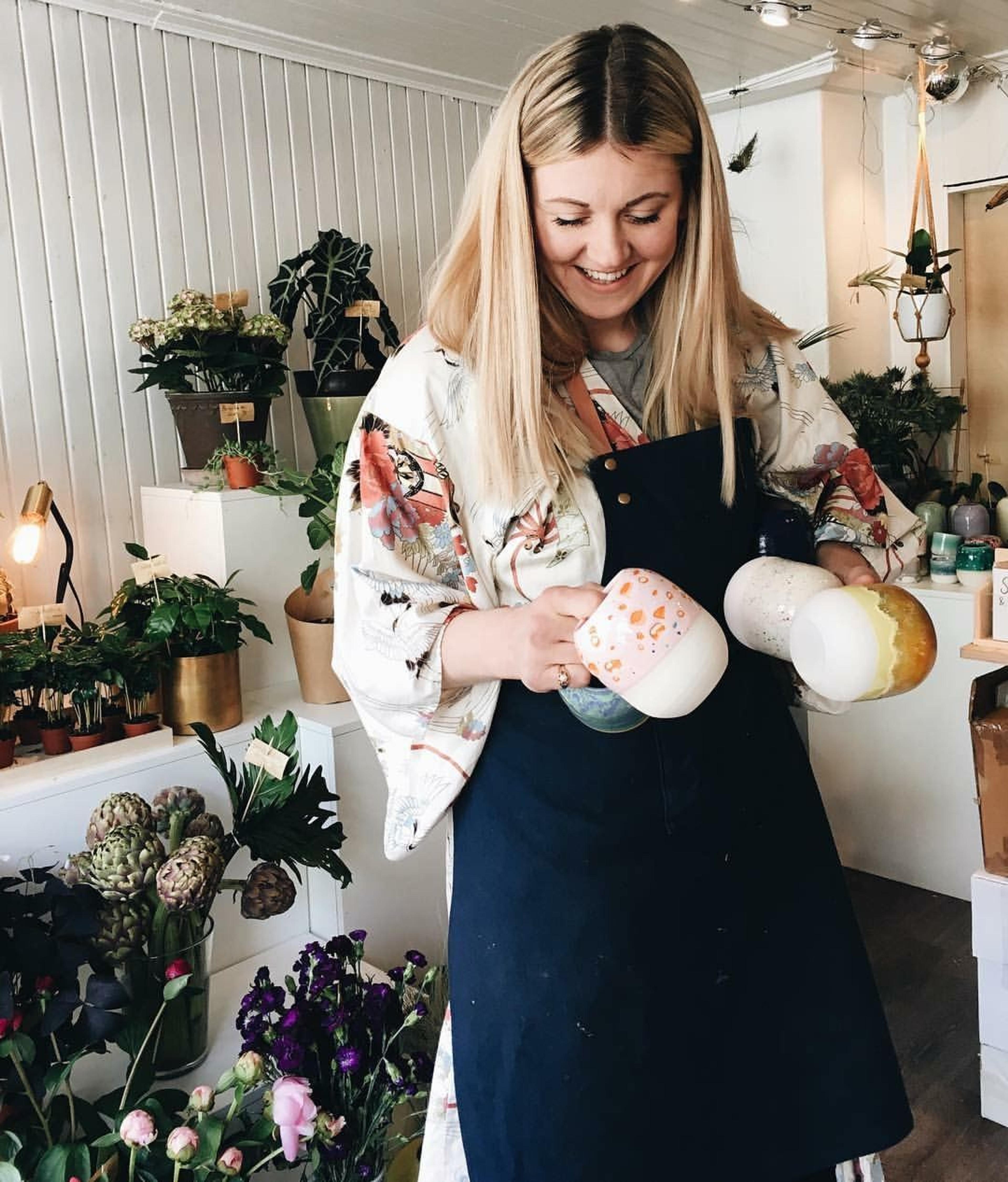 Innehaveren på Bakklandet Blomster viser opp noen av sine produkter i butikken