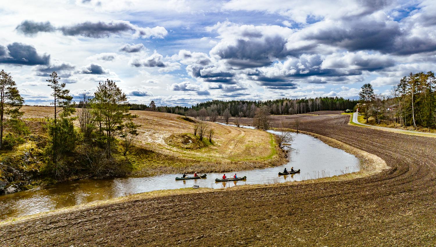 padler kano mellom jorder