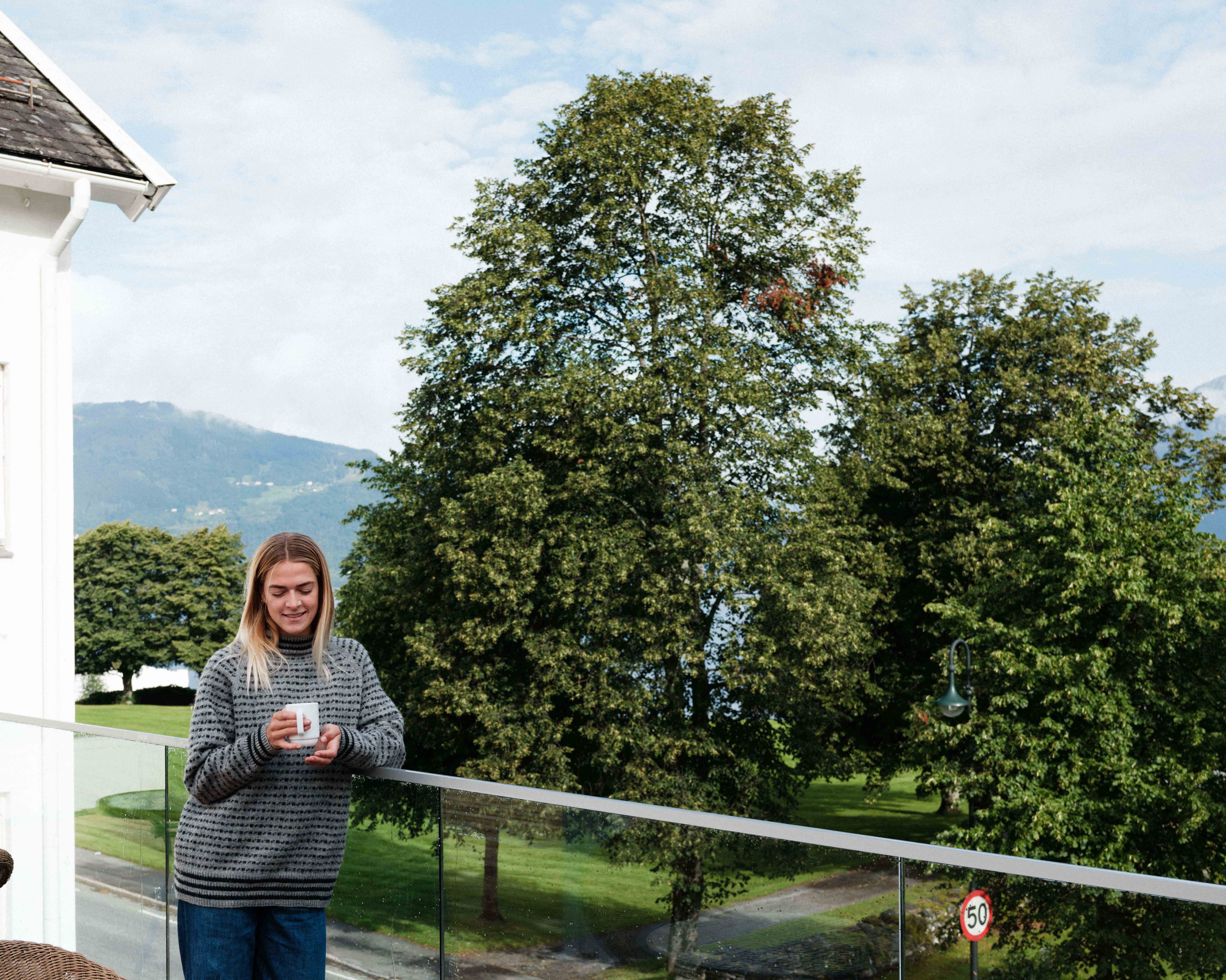Gjest som slappar av på uteserveringa med utsikt mot Hardanger-naturen.