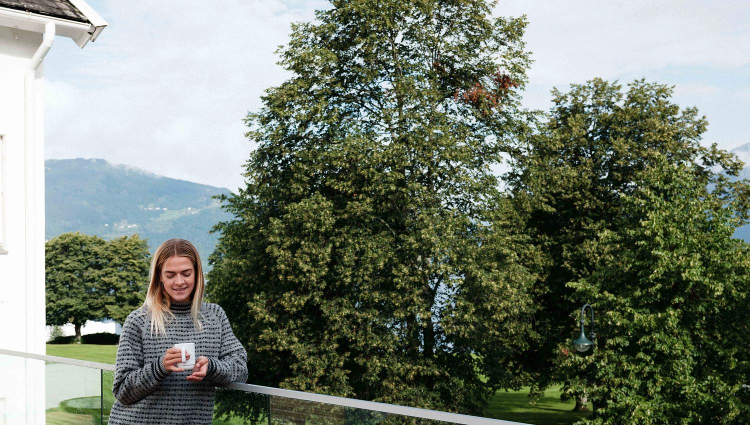 Gjest som slappar av på uteserveringa med utsikt mot Hardanger-naturen.