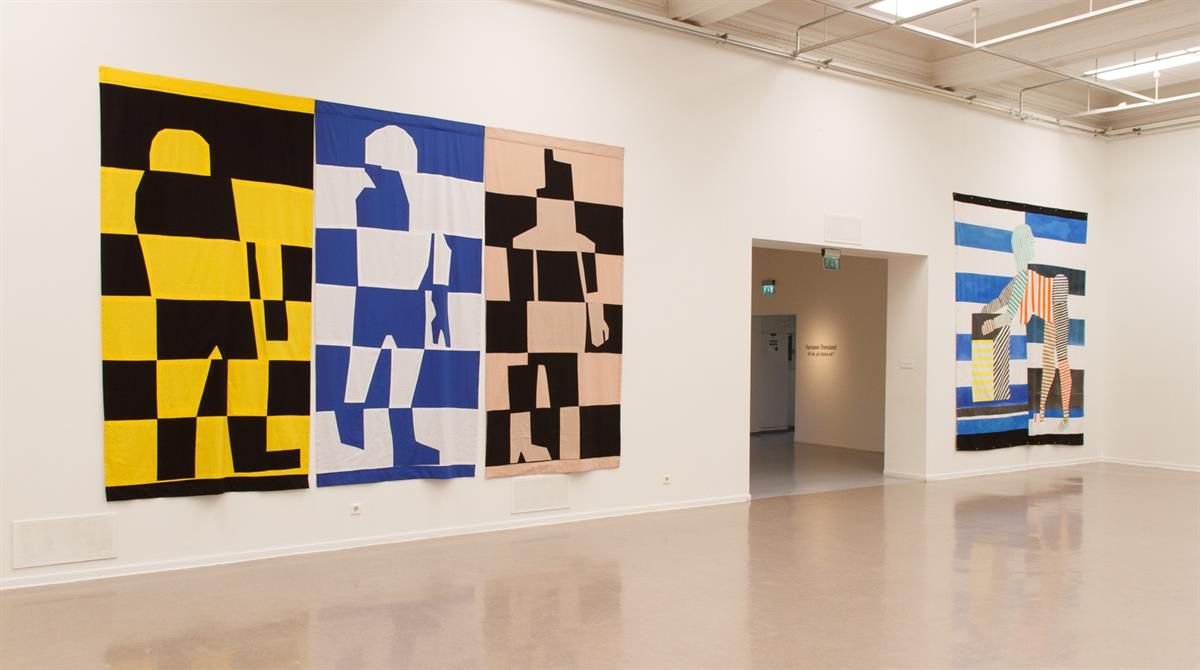 Kunst i kunstbanken - Store geometriske malerier i gult, blått og svart montert i lyst gallerirom.