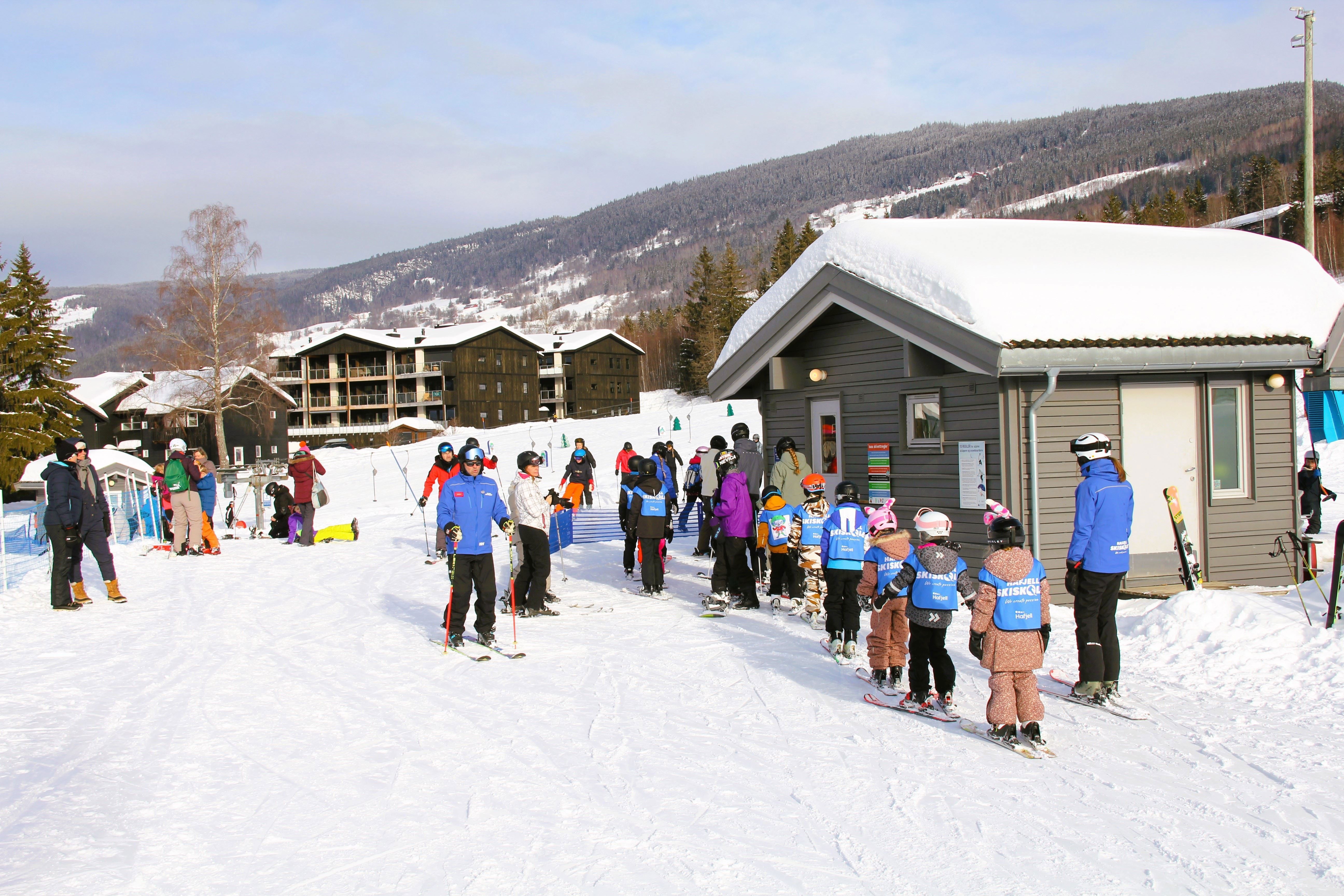 A group of people skiing in front of a building.