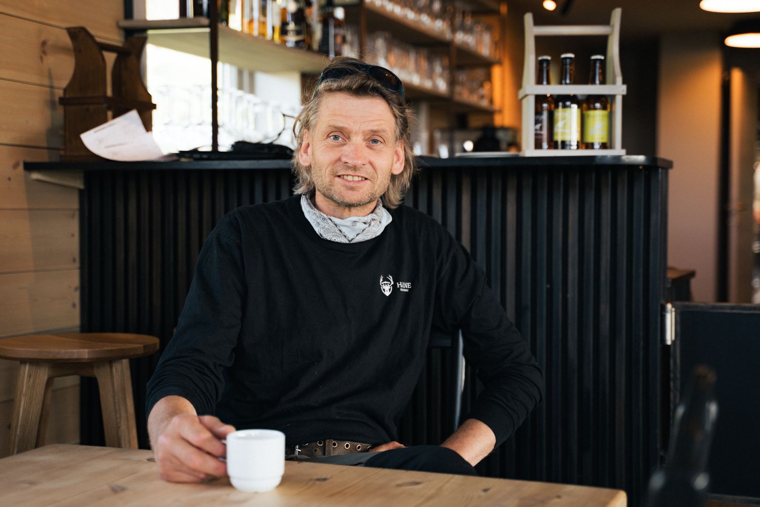 Eieren på Halne fjellstugu sitter ved et bord og holder en kopp kaffe.