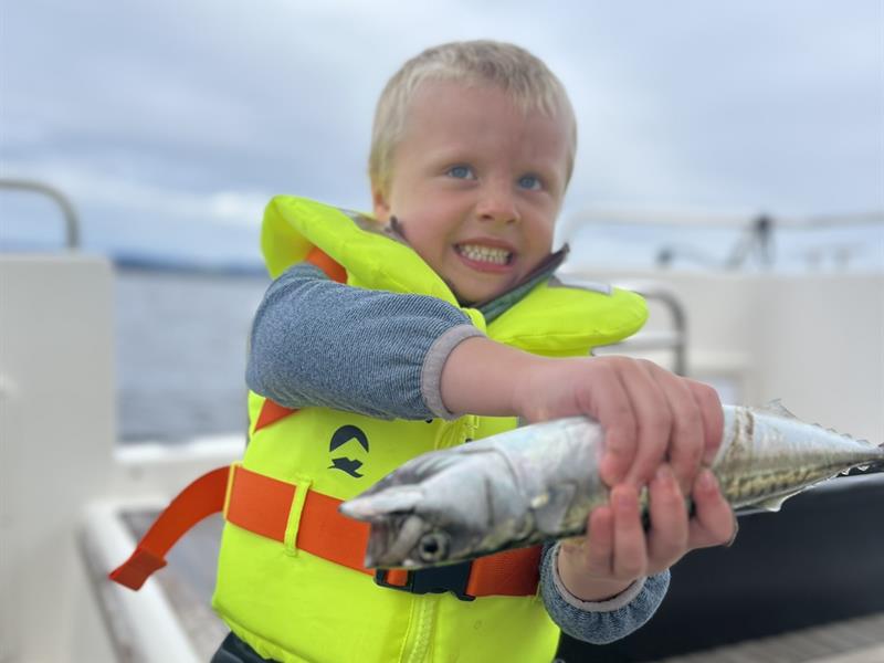Gutt i redningsvest med selvfanget fisk
