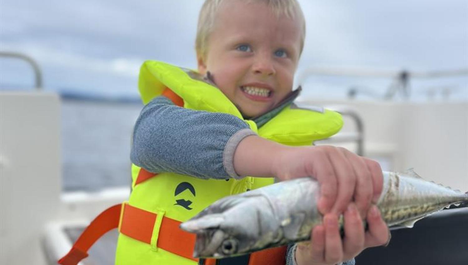 Gutt i redningsvest med selvfanget fisk