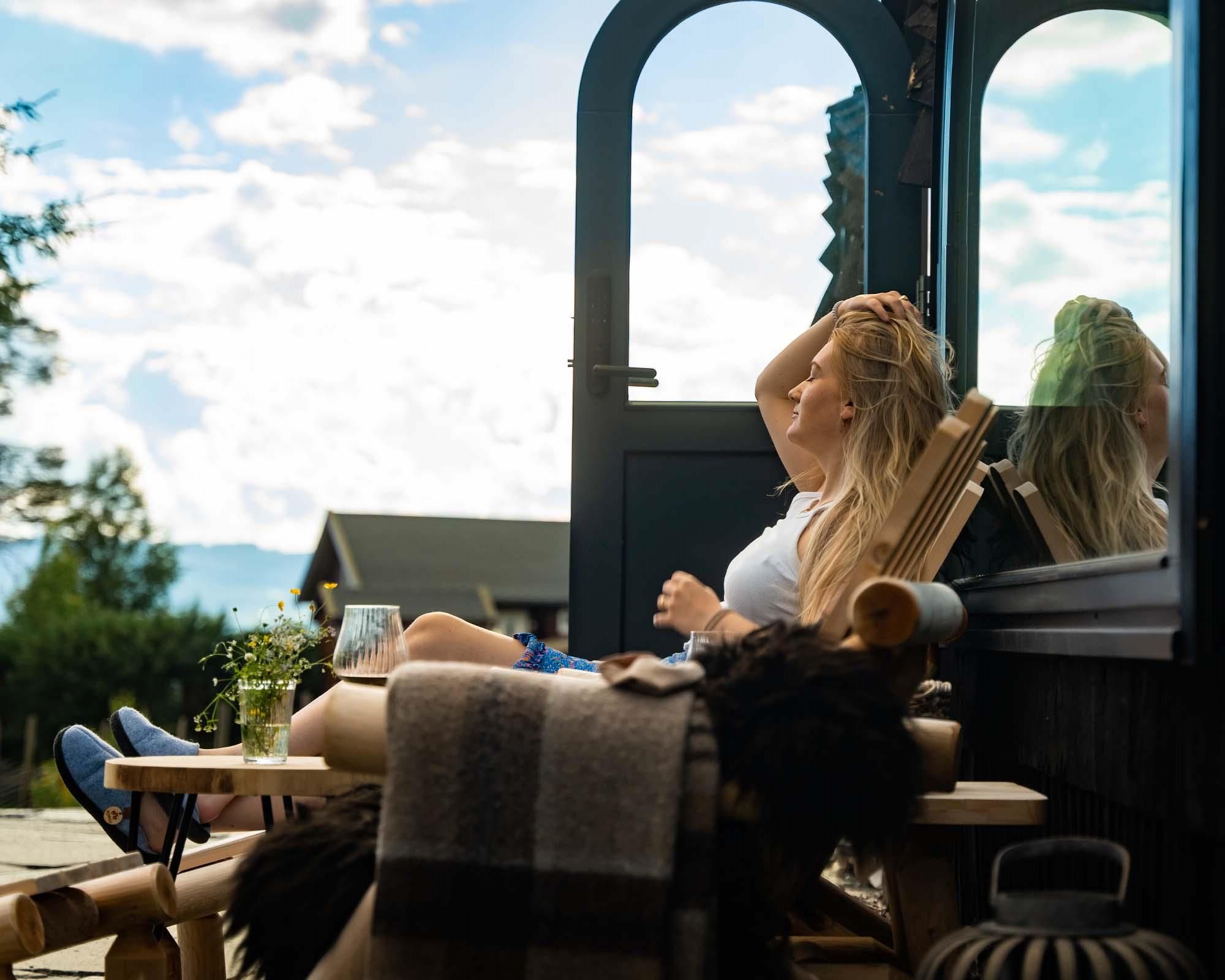 dame som sitter i en stol foran en hytte med utsikt