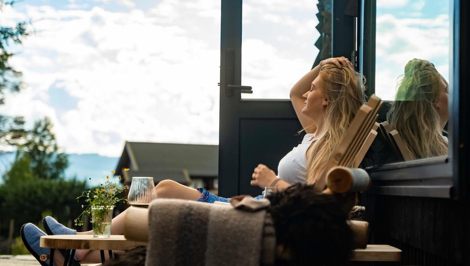 dame som sitter i en stol foran en hytte med utsikt