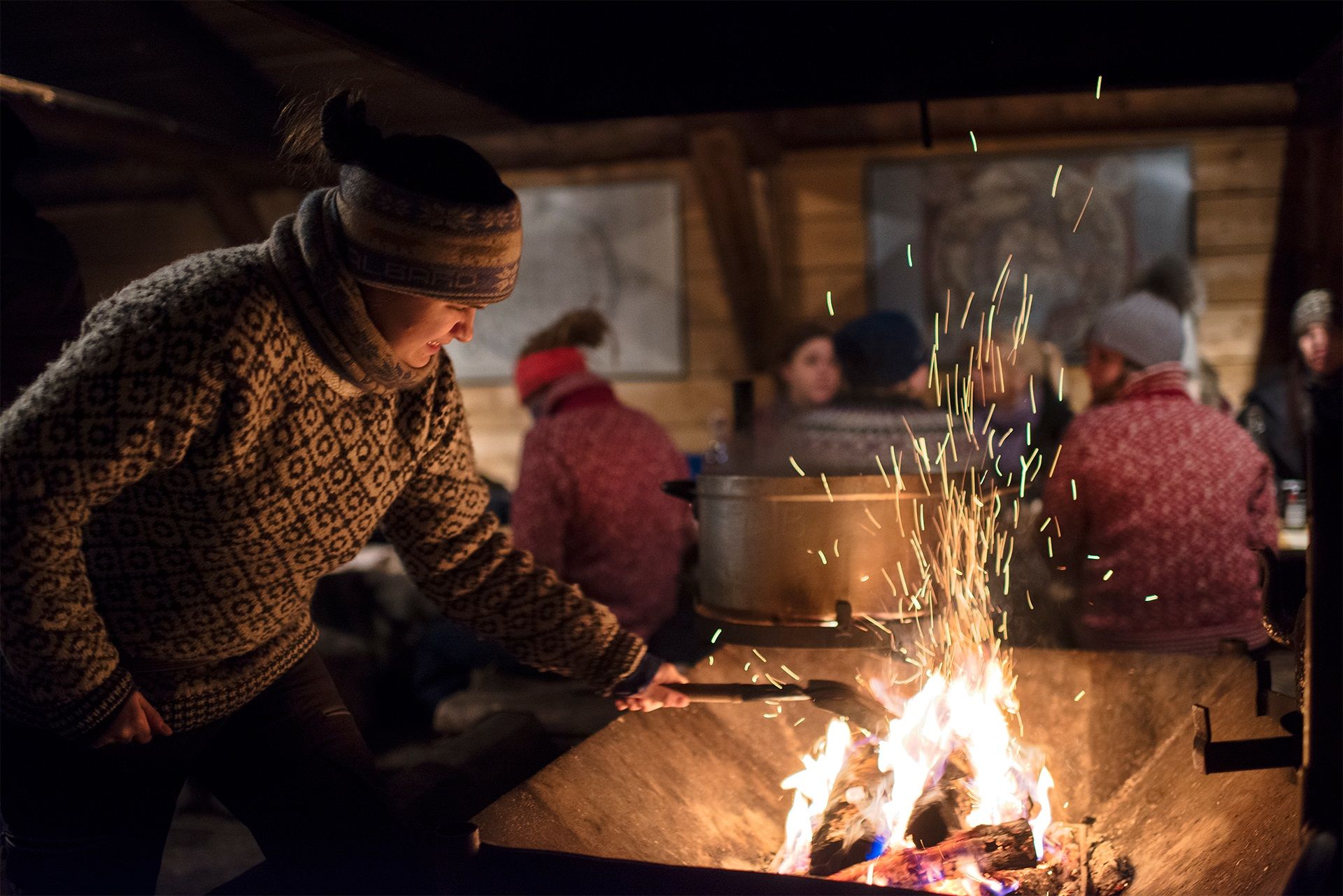A host at Camp Barentz putting a log on a fire