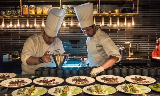 To kokker som forbereder matretter til servering på et kjøkken