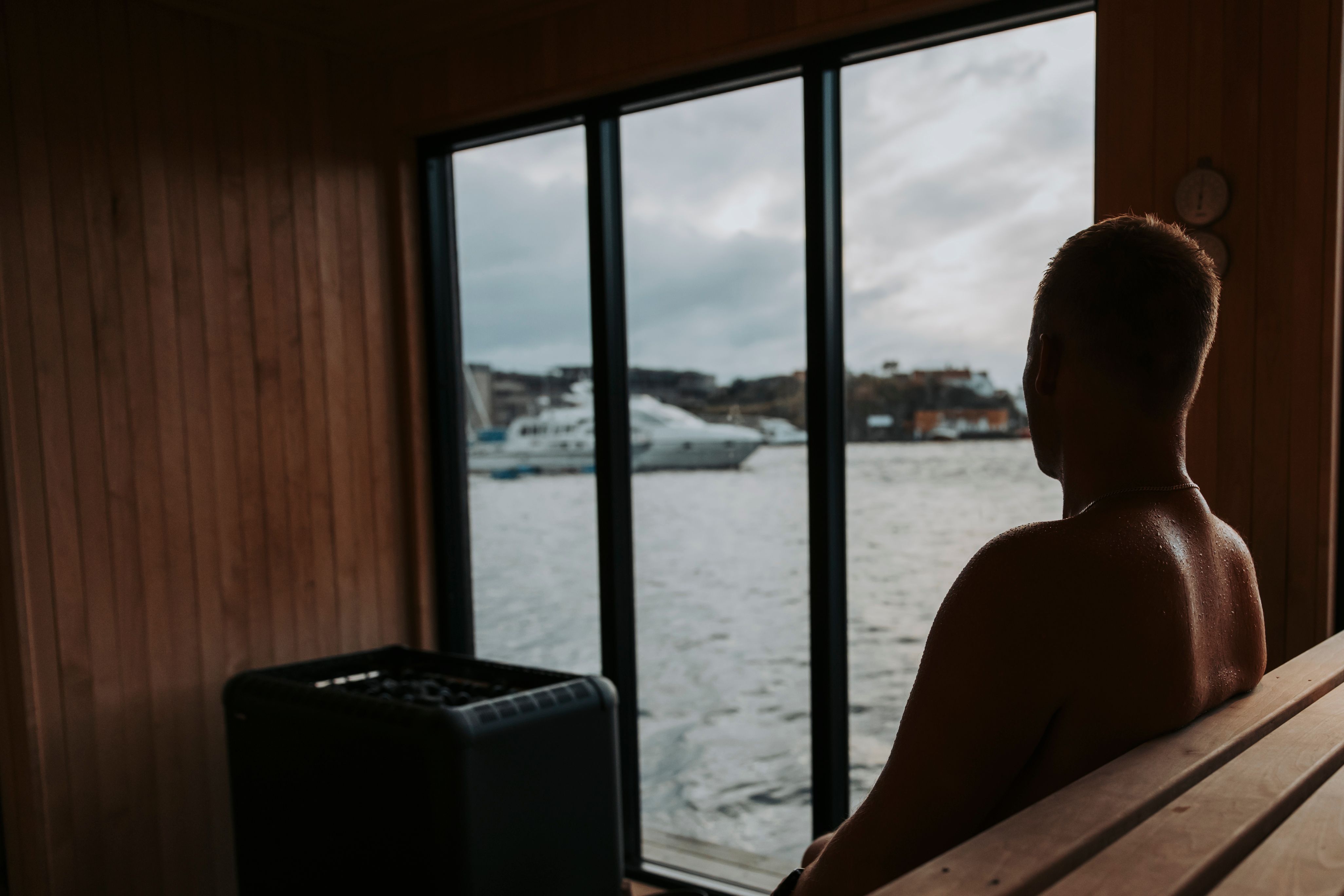 En mann som sitter inne i badstubåten Pysen og ser ut av vinduet