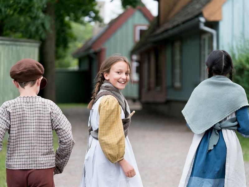 Tre barn i tradisjonelle klær på Norsk Folkemuseum.