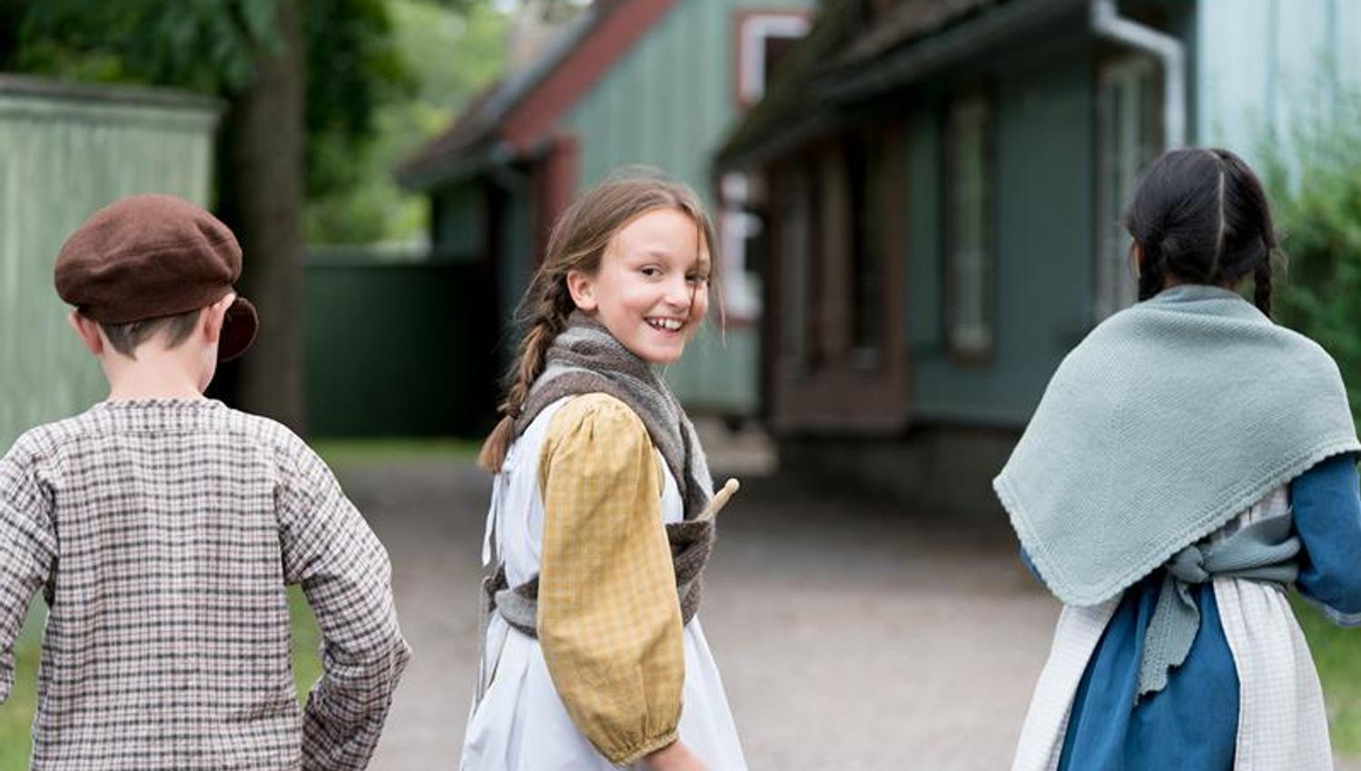 Tre barn i tradisjonelle klær på Norsk Folkemuseum.