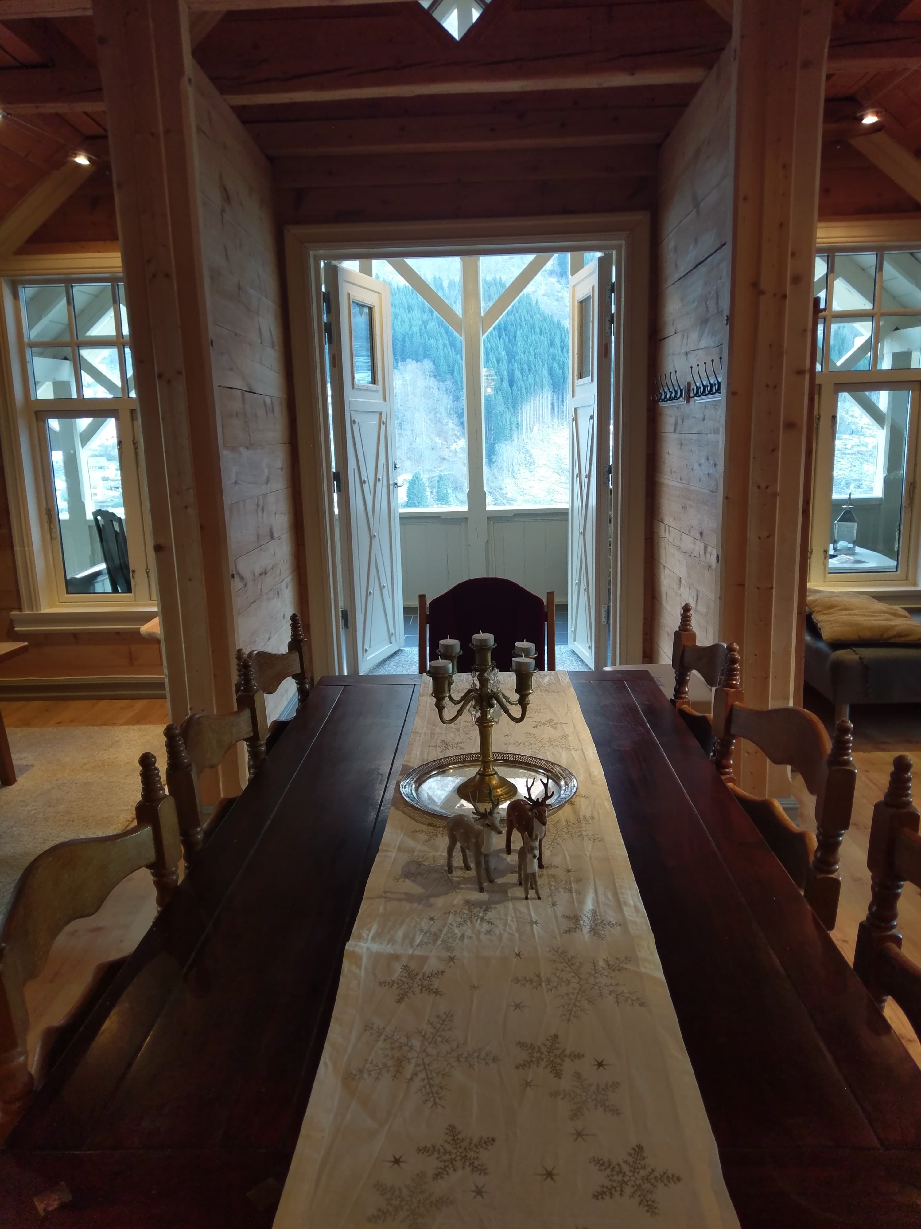 Stemningsfull spisestove på Vikinghaug Apartments med langbord og utsikt mot verandaen og fjellsidene rundt Hardanger.