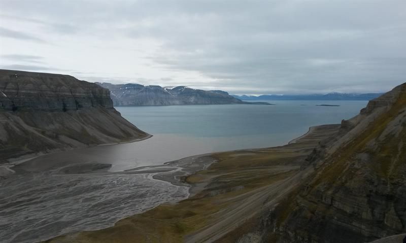 A fjord surrounded by mountains with a river delta in the foreground
