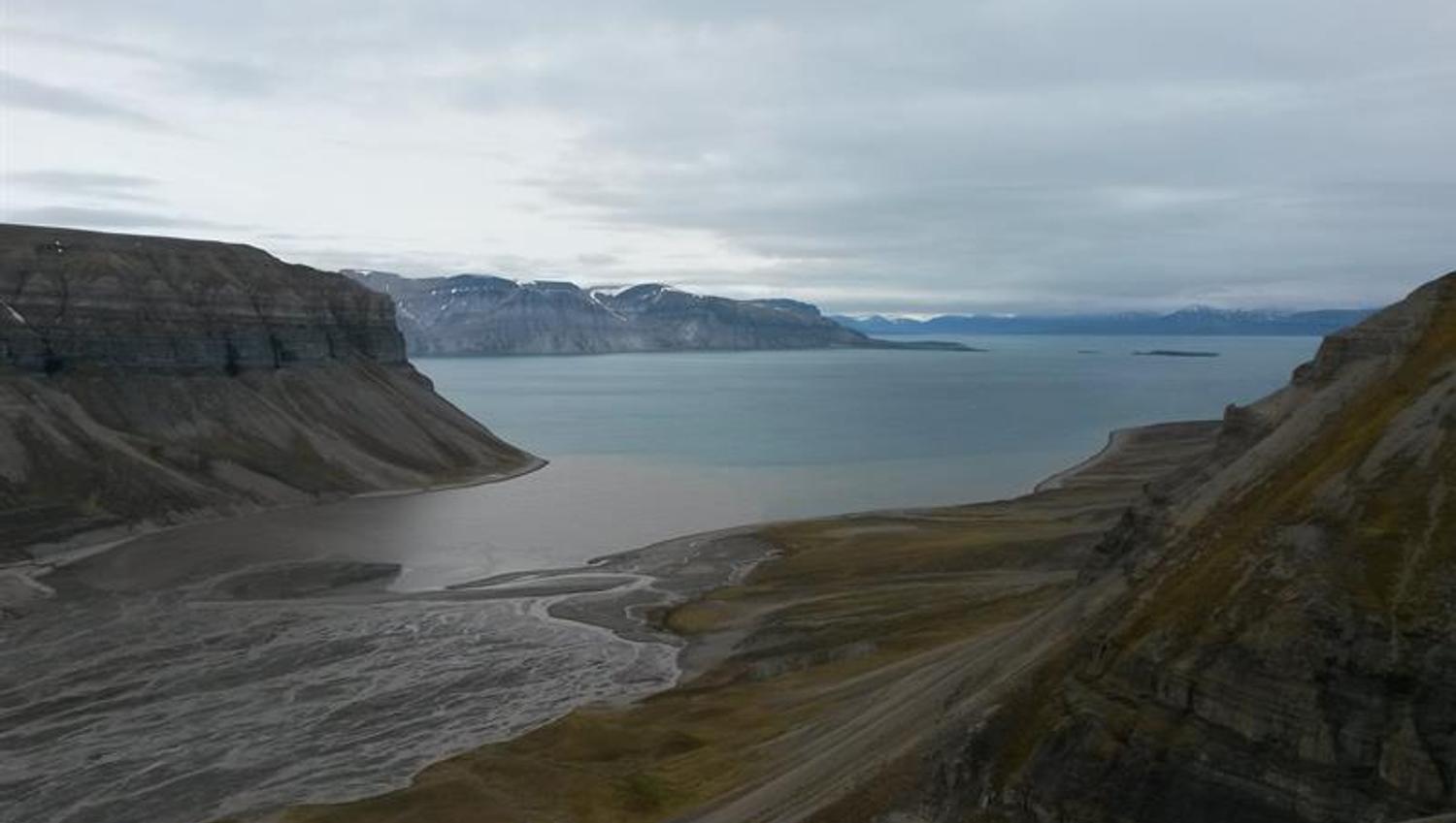 A fjord surrounded by mountains with a river delta in the foreground