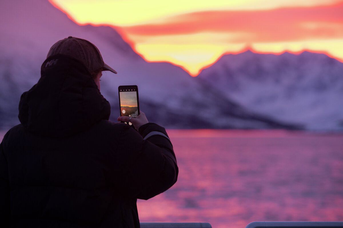 person taking a mobile photo of colourful Arctic sky in the Tromsø region