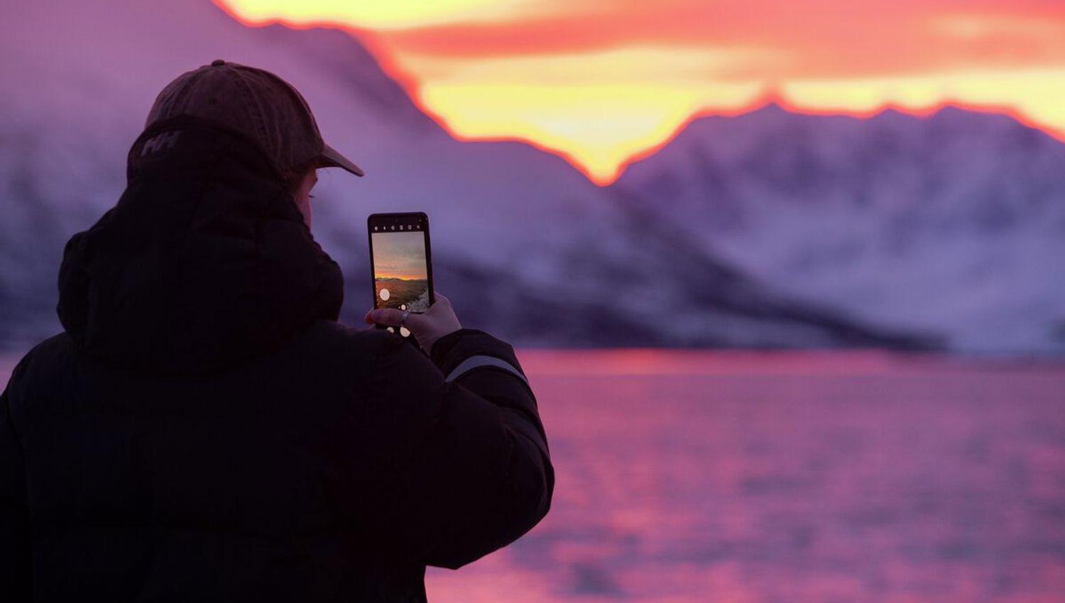 person taking a mobile photo of colourful Arctic sky in the Tromsø region