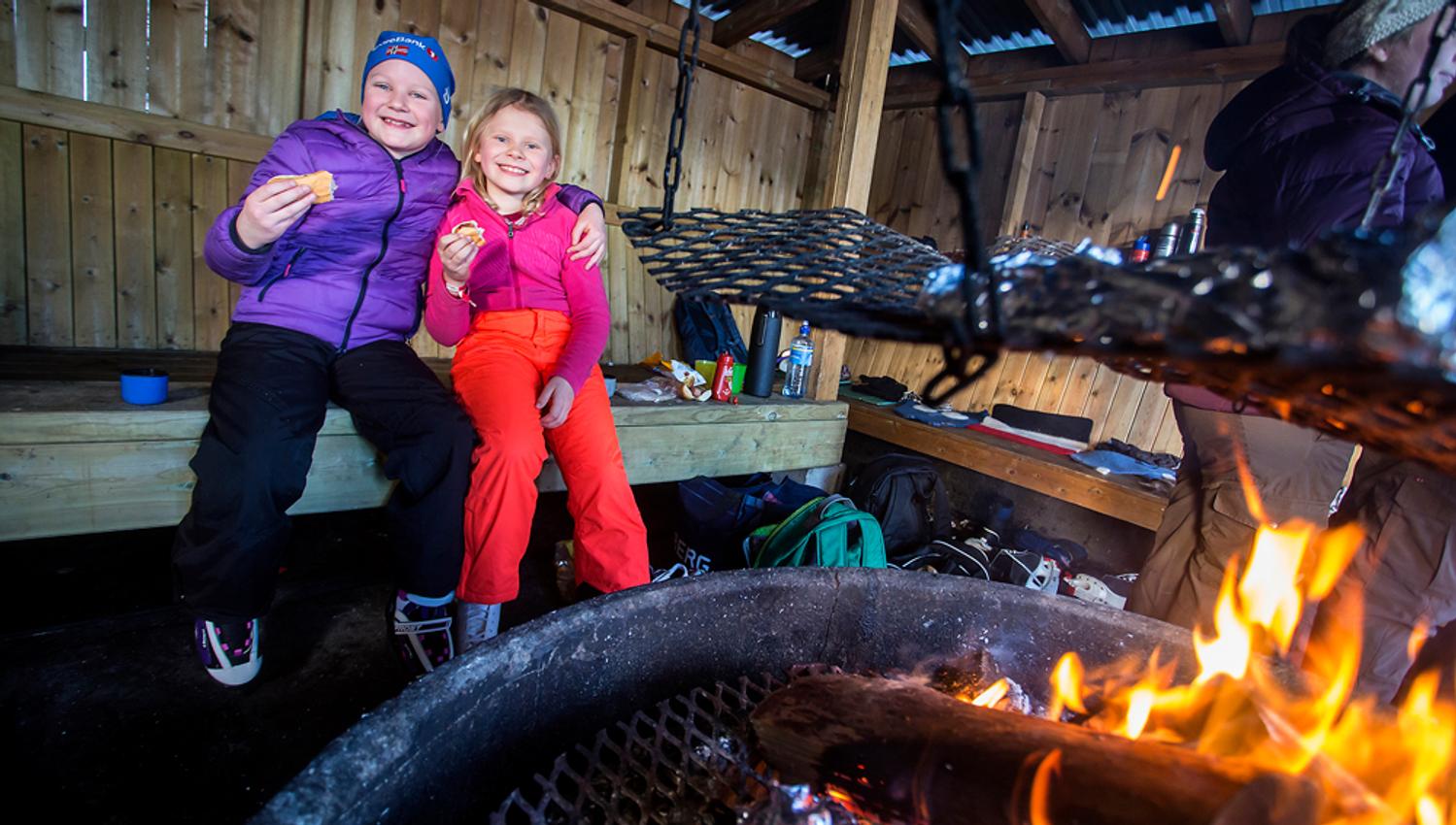 barn koser seg med pølse på bålplassen ved skøytebanen i Skien fritidspark