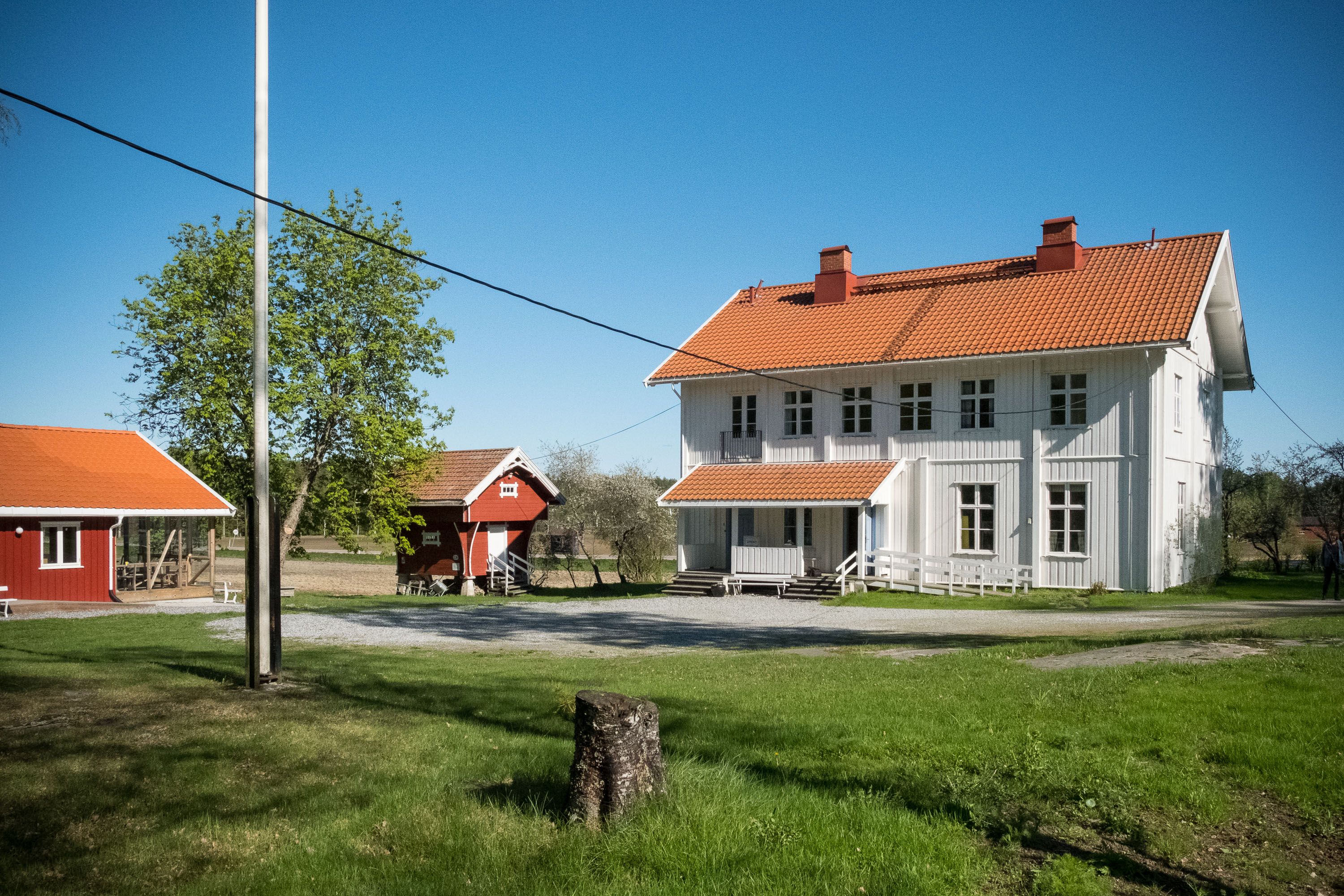 Stor hvit gammel bygning med rødt tak og stabbur