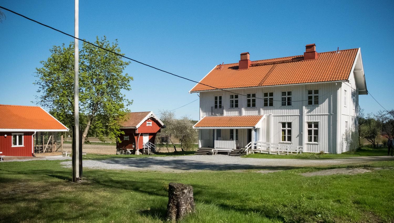 Stor hvit gammel bygning med rødt tak og stabbur