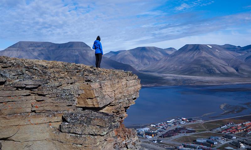 person standing on mountaintop looking at the view over town 