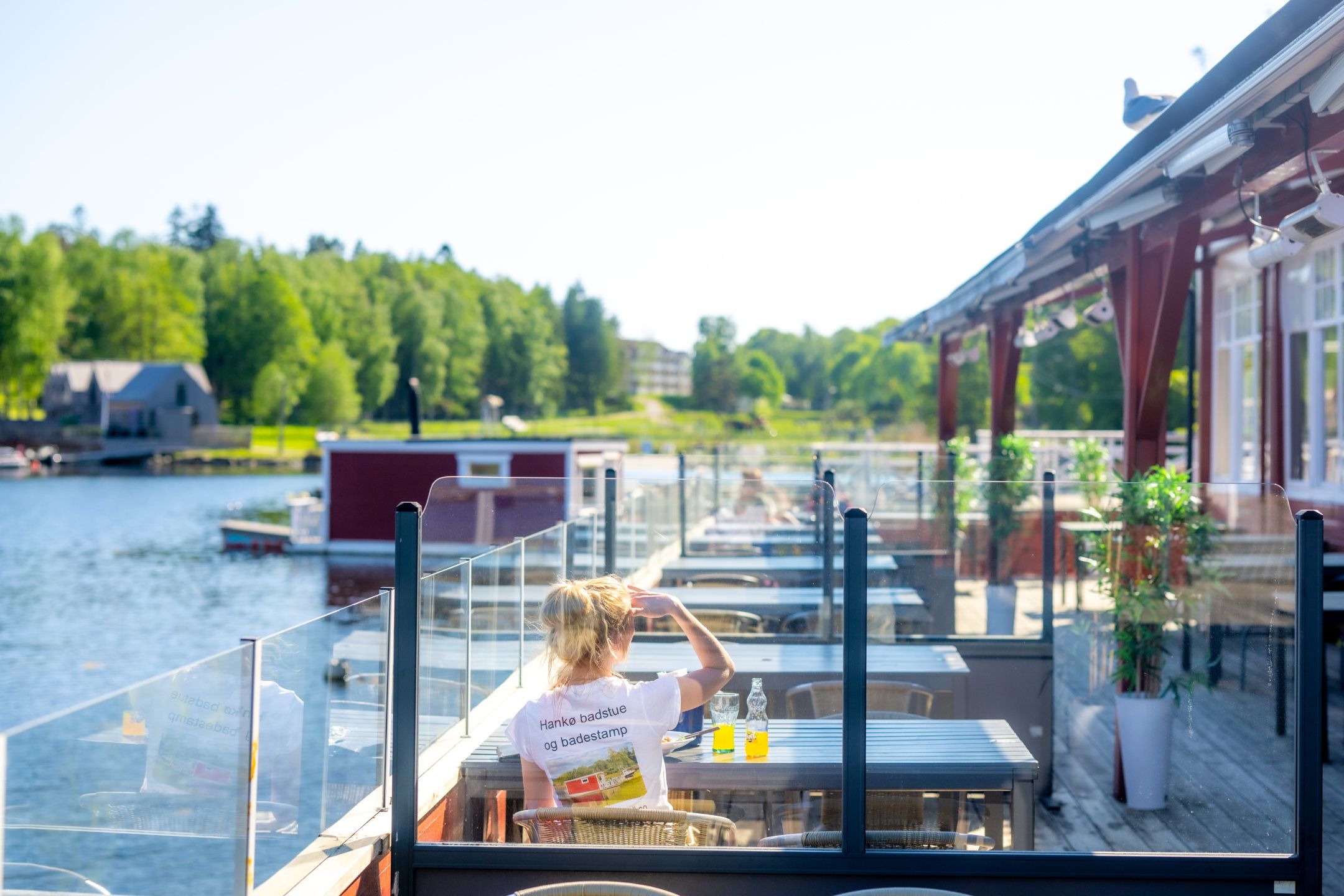 Outdoor dining area by the waterfront, guests enjoying meals with a view of the marina and lush surroundings.