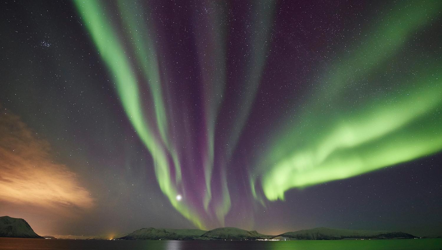 et nordlys som går parallelt på himmelen over havet mot land