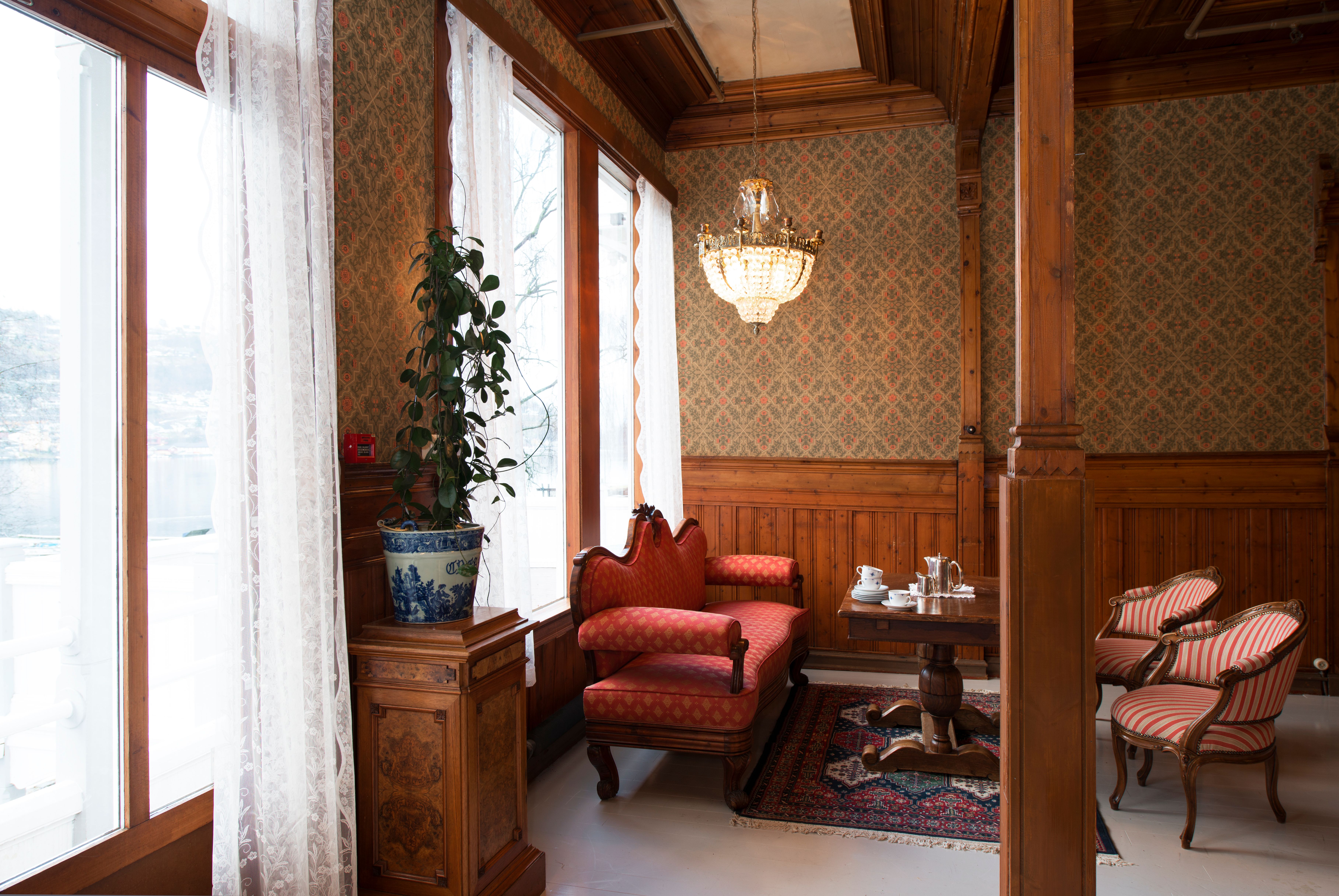 Elegant salong på Thon Hotel Sandven, med historiske møblar og utsikt mot Hardangerfjorden.