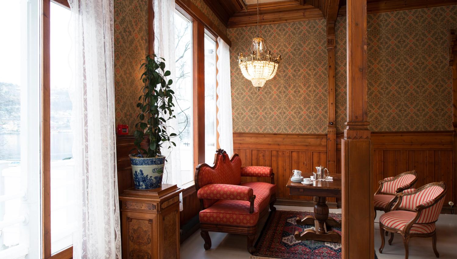 Elegant salong på Thon Hotel Sandven, med historiske møblar og utsikt mot Hardangerfjorden.