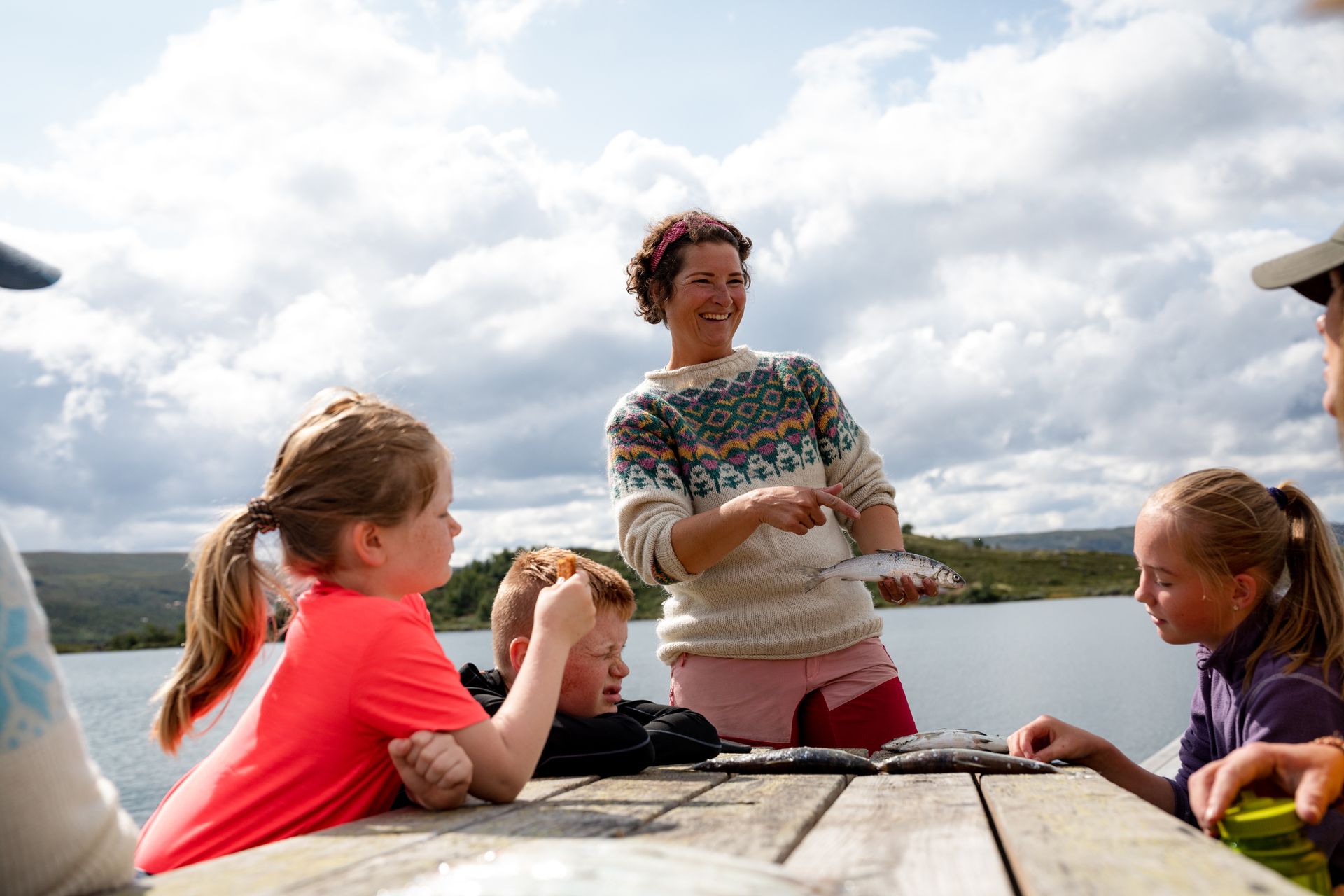 Hilde shows off their catch ( fish )  to the children 