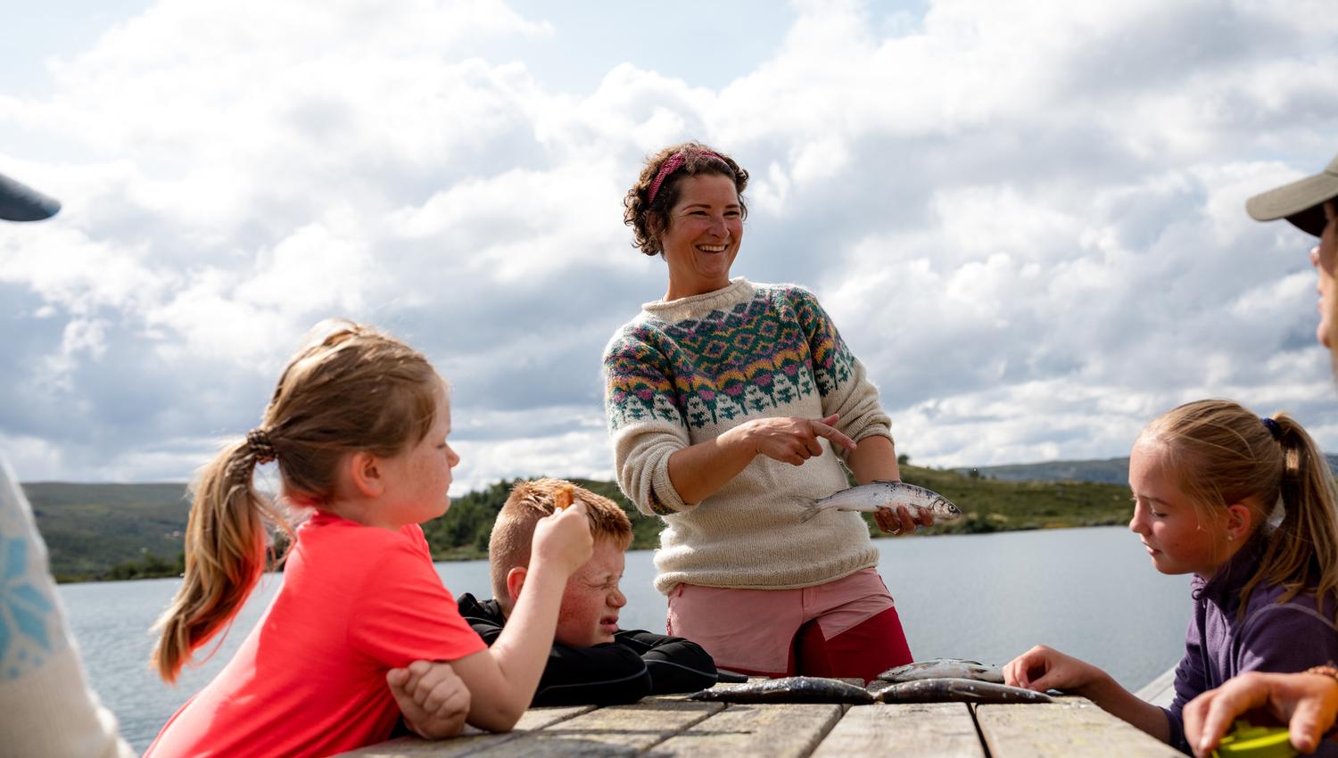 Hilde shows off their catch ( fish ) to the children