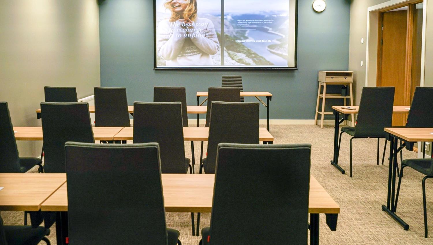 Moderne møterom med prosjektor og komfortable stolar.