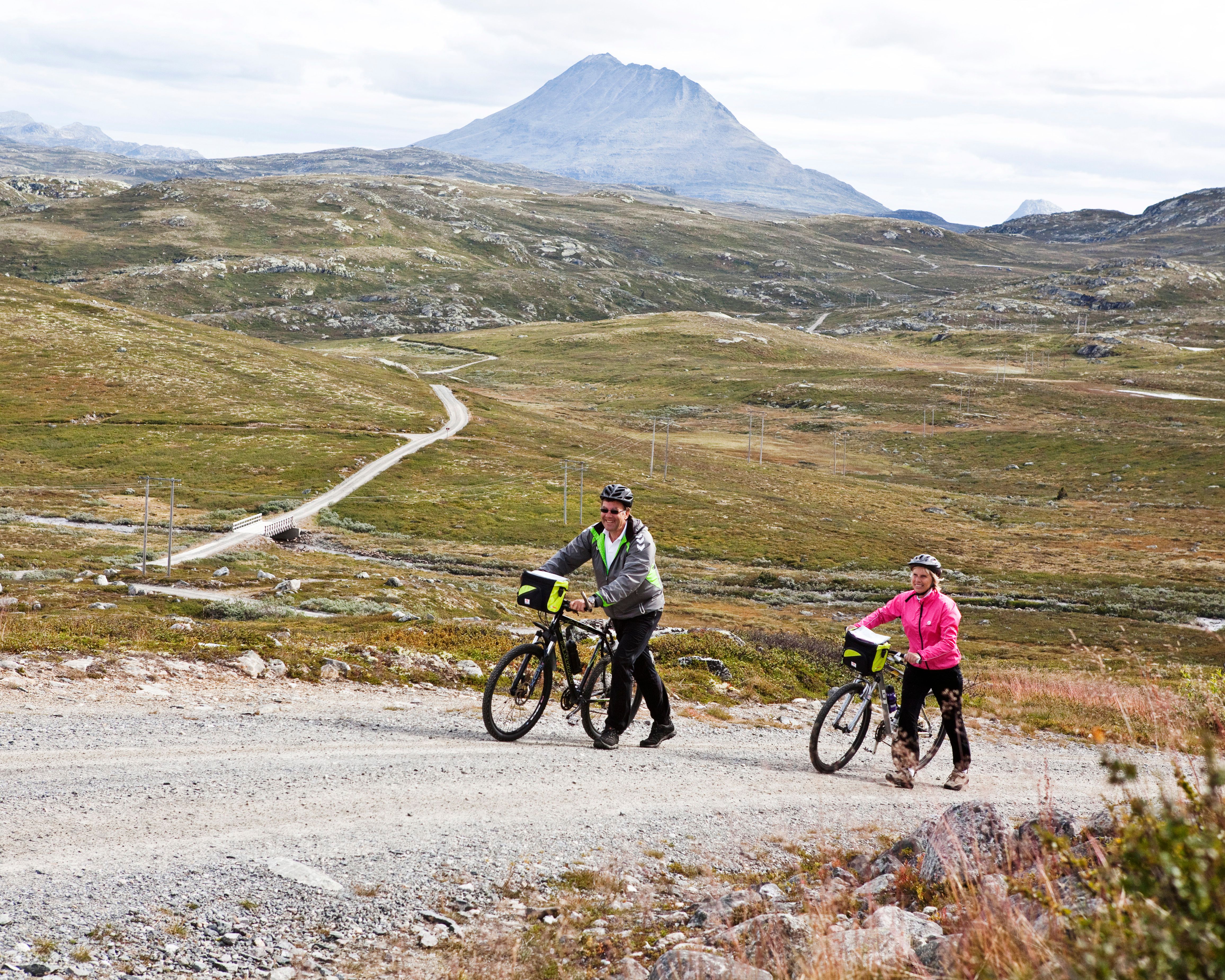 eldre par dytter syklene sine og Gaustatoppen i bakgrunn