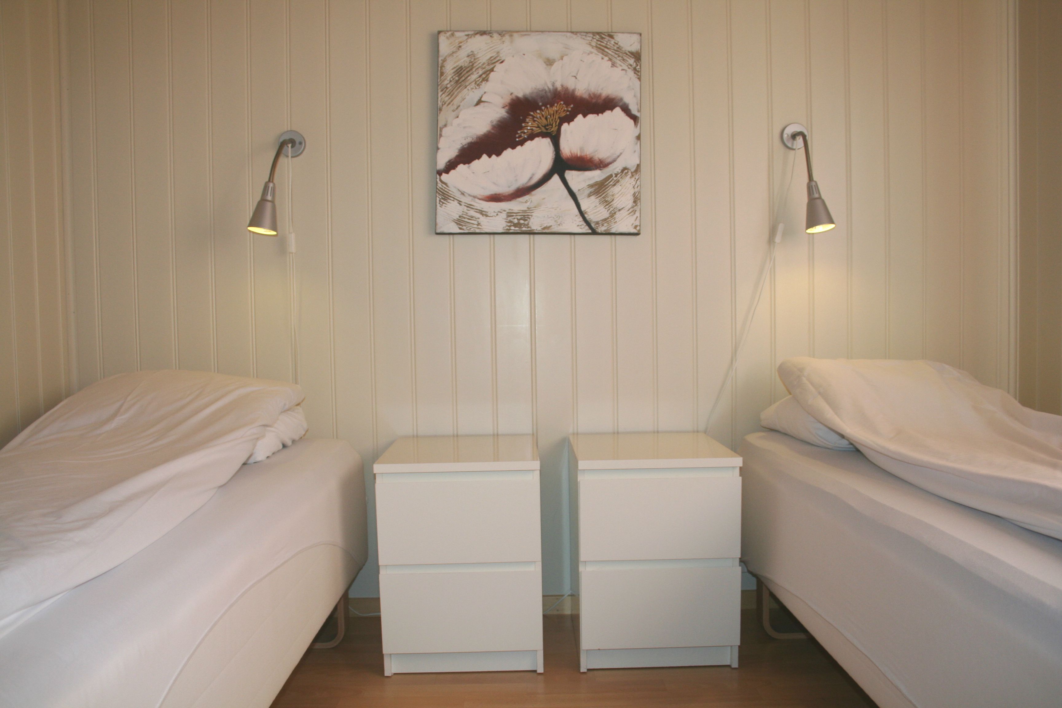 Soverom med to enkeltsenger og veggkunst i hytte på Oddland Camping.