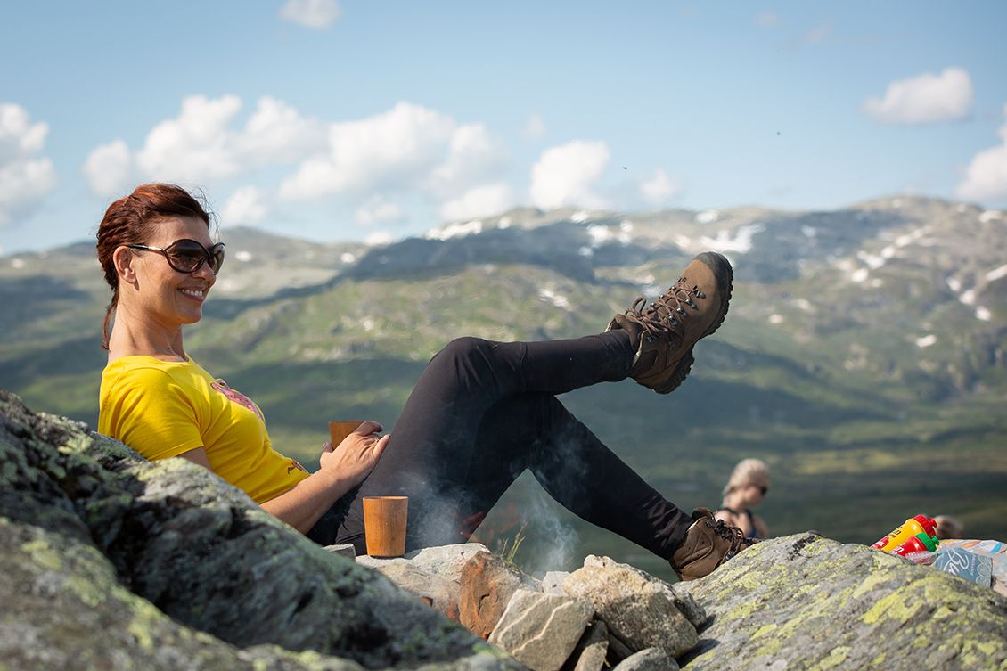 dame sitter på fjellet og nyter en kaffe
