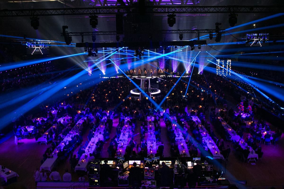 Konsertsal fylt med publikum, med blå scenelys og laserstråler som lyser over rommet.