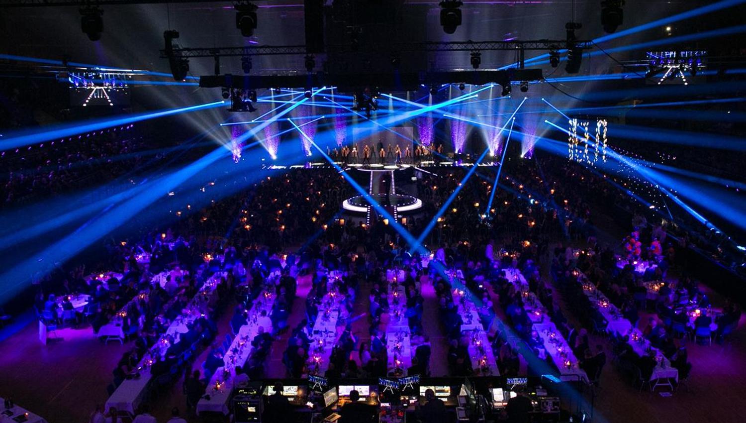 Konsertsal fylt med publikum, med blå scenelys og laserstråler som lyser over rommet.