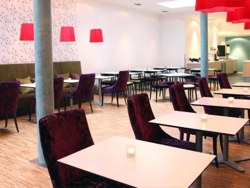 Bright and modern dining area with purple chairs, white tables, and red lamps.