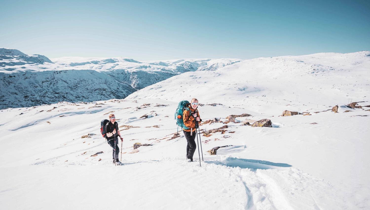 To deltakarar på vintertur med ryggsekkar og snøsko nær Trolltunga.