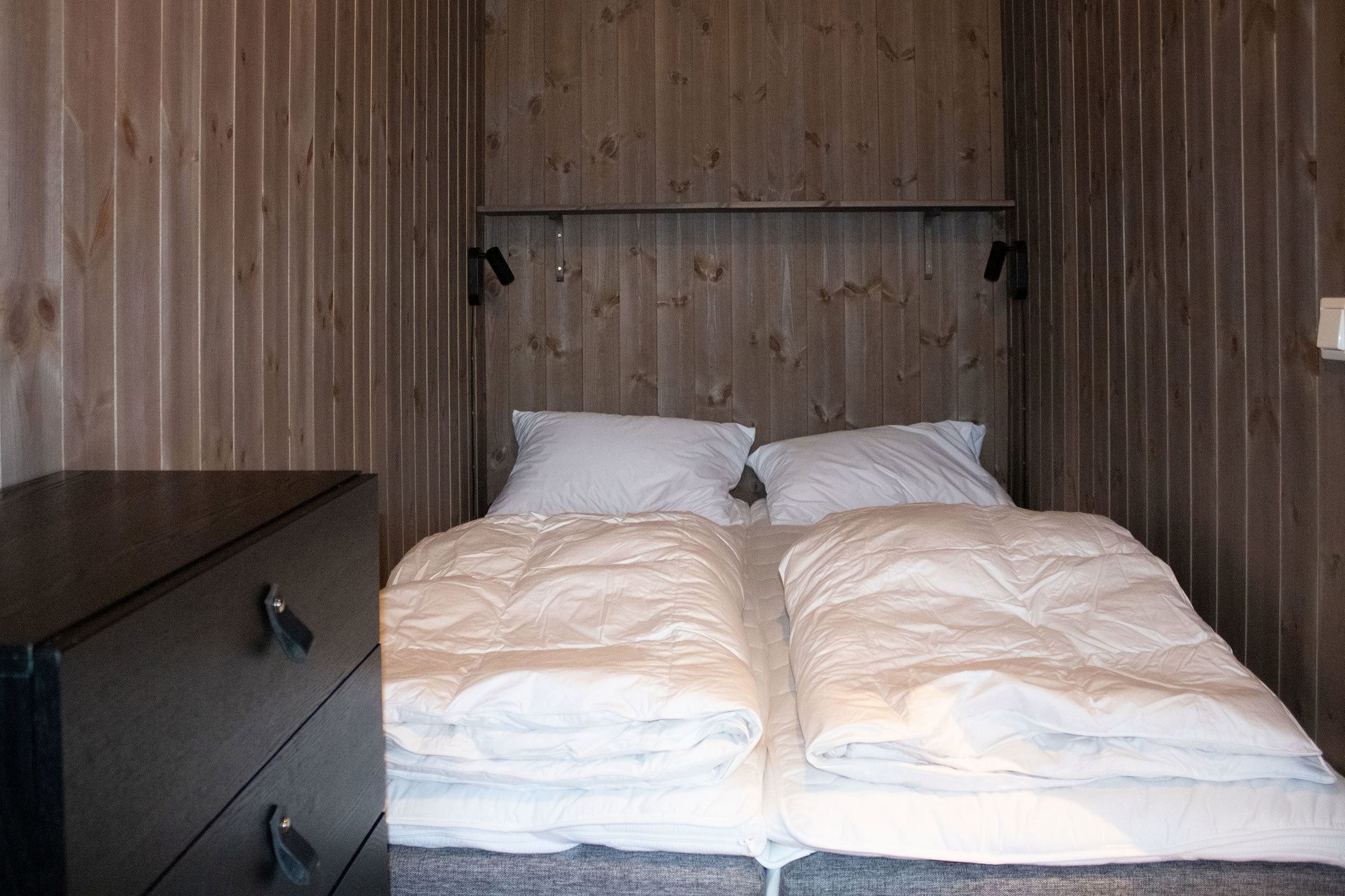A bed with white sheets and pillows in a room.