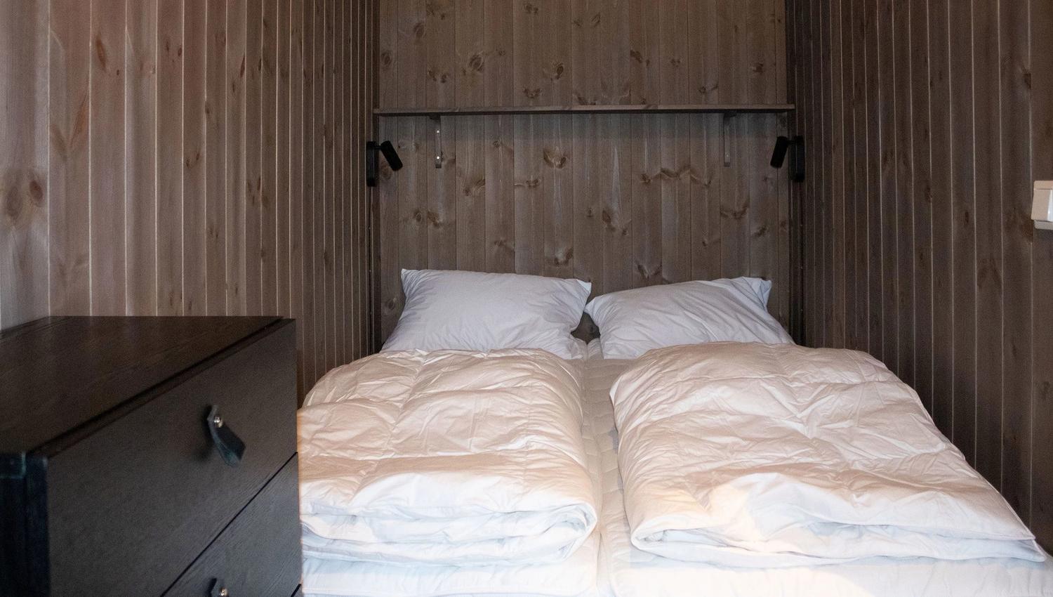 A bed with white sheets and pillows in a room.