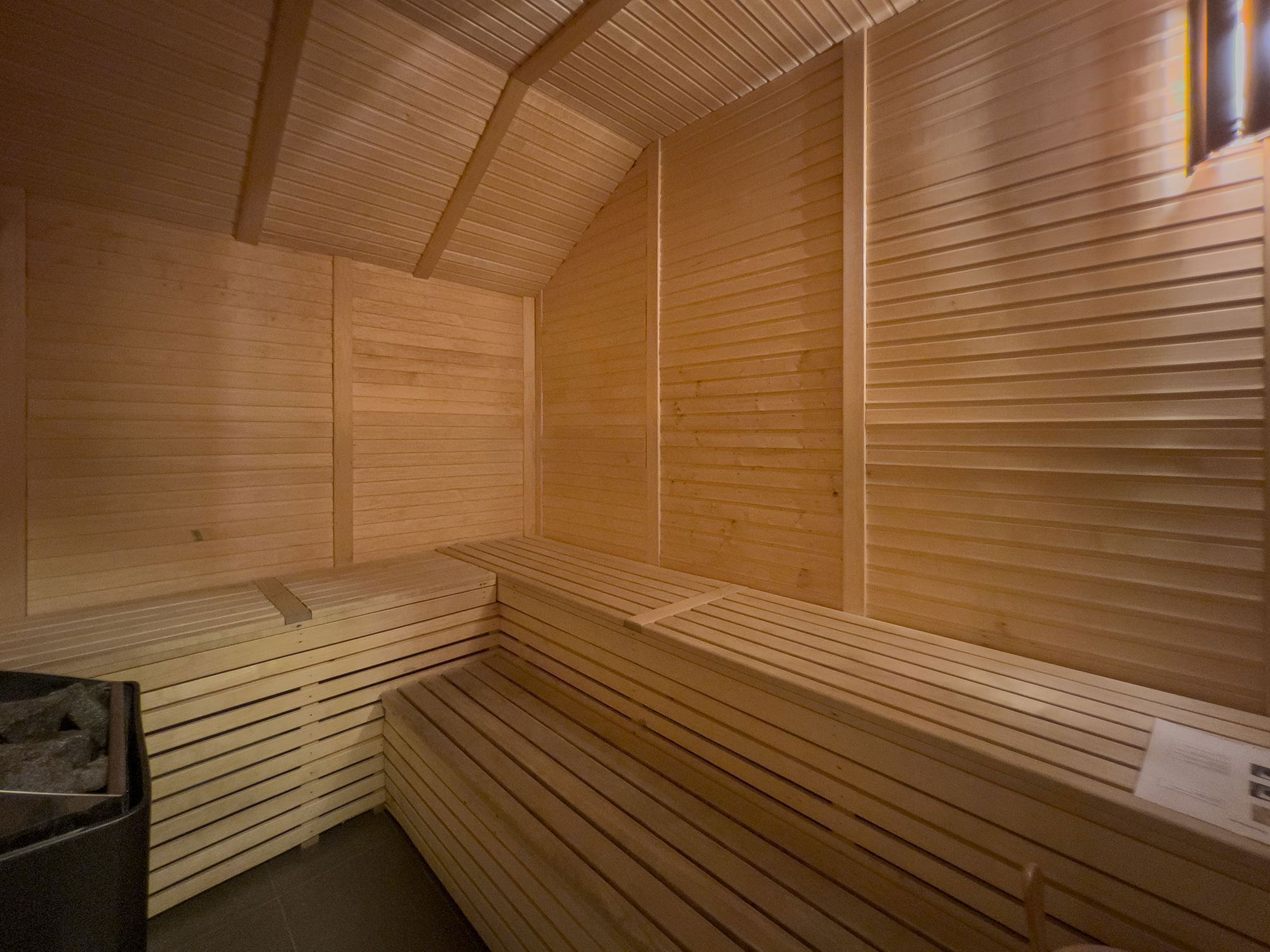 A wooden sauna with ceiling and tile floor.