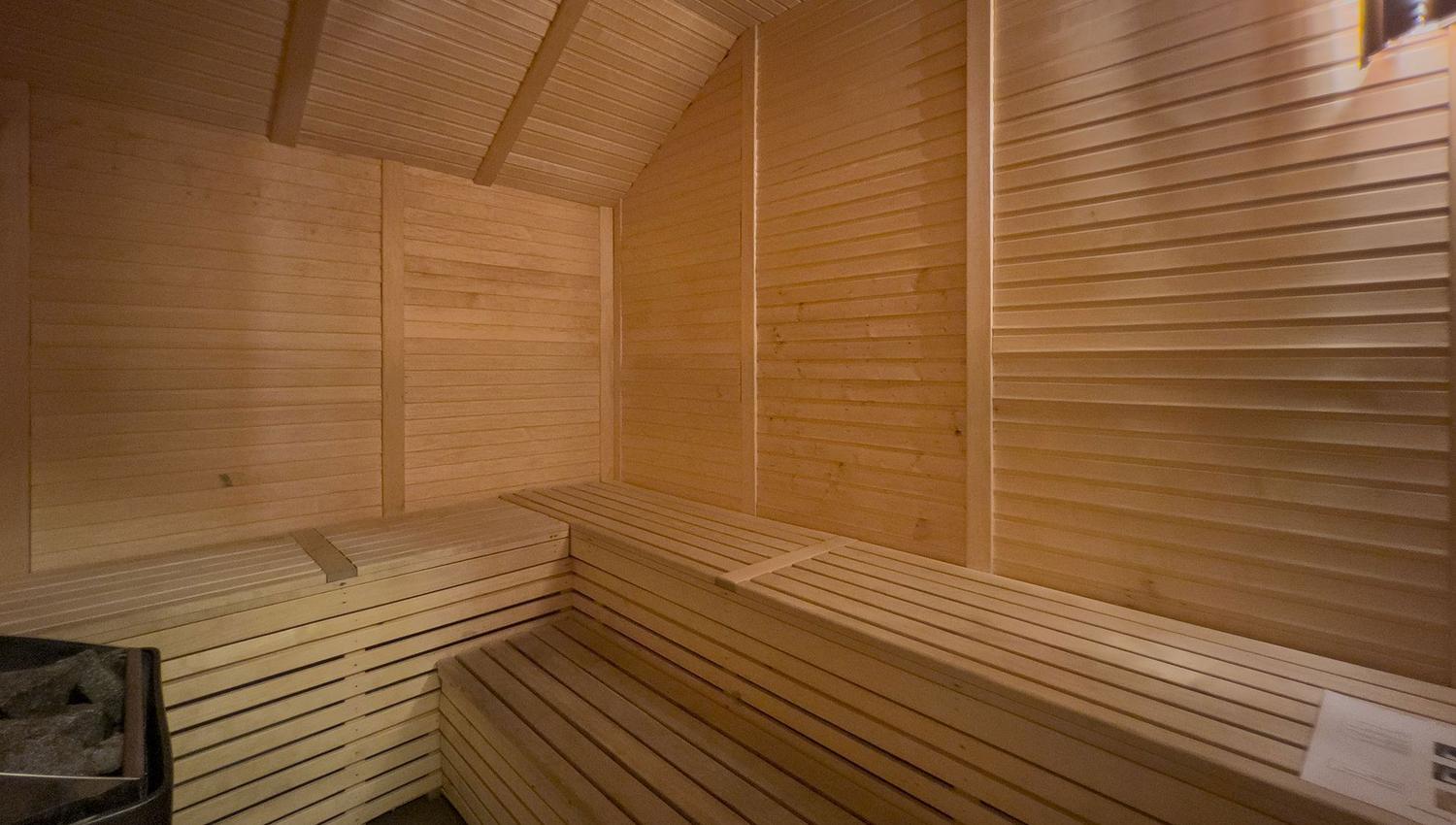 A wooden sauna with ceiling and tile floor.